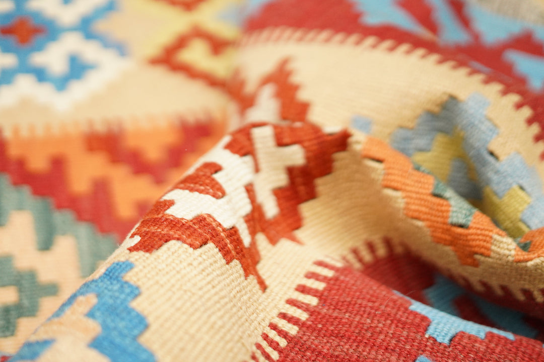 Close-up of a handcrafted Persian kilim rug in soft beige and vibrant colours, illustrating Oba Gallery’s cleaning, restoration, home visit, and worldwide delivery services.